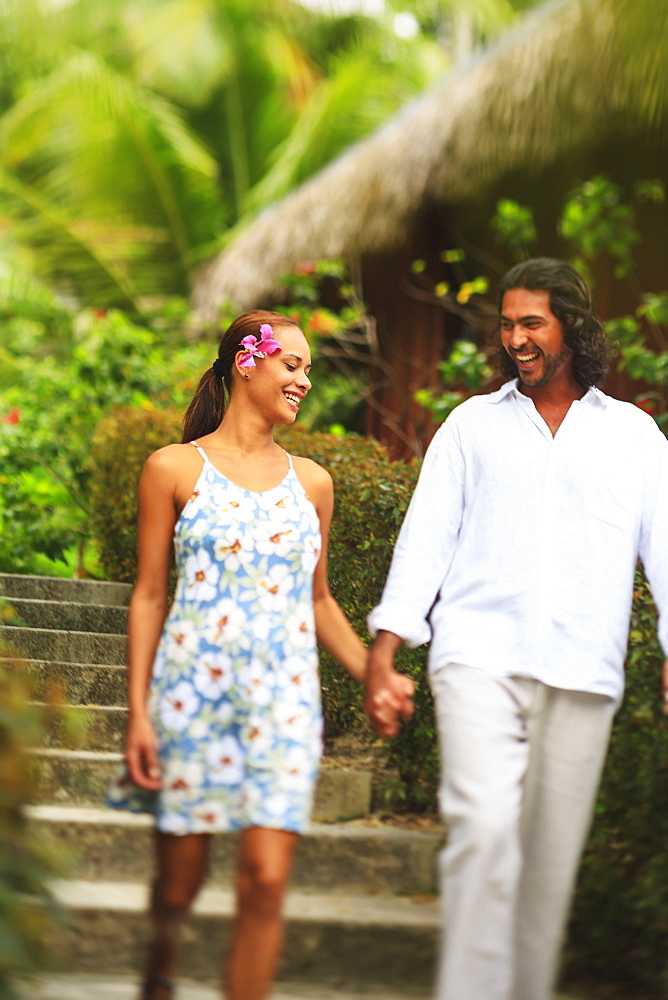 A man and woman hold hands and walk through the bora bora nui resort and spa, Bora bora island society islands french polynesia south pacific