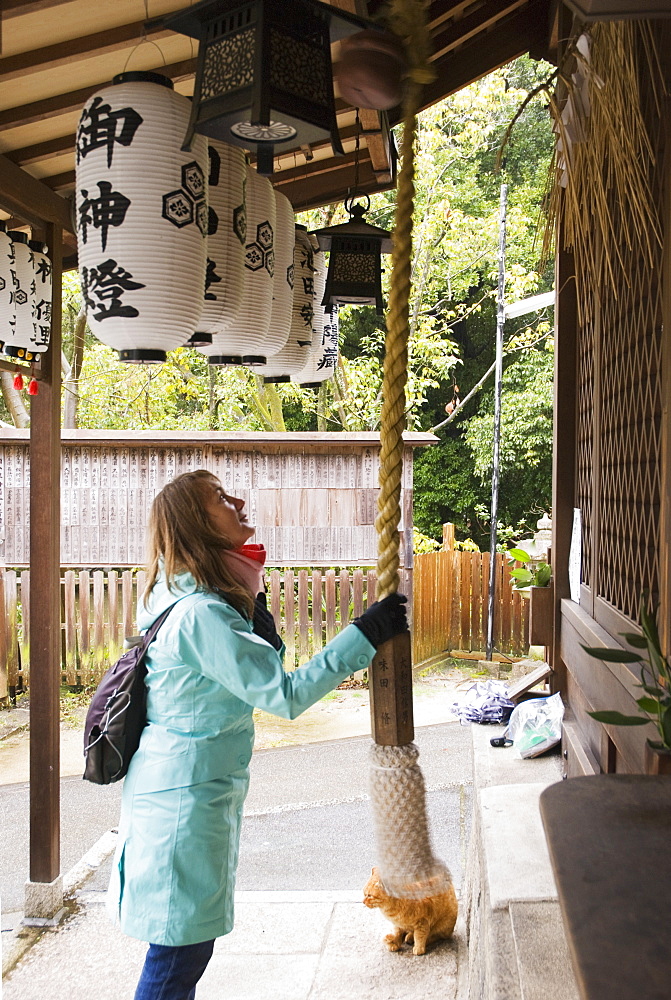 Female tourist ringing the bell of a japanese shrine, Kyoto japan