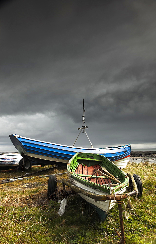 Rowboats sitting on trailers on the shore under storm clouds, Boulmer northumberland england