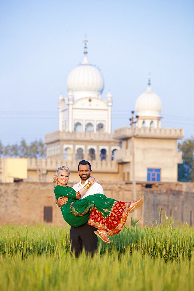 Portrait Of A Mixed Race Couple Her Wearing A Sari With A Temple In The Background, Ludhiana, Punjab, India