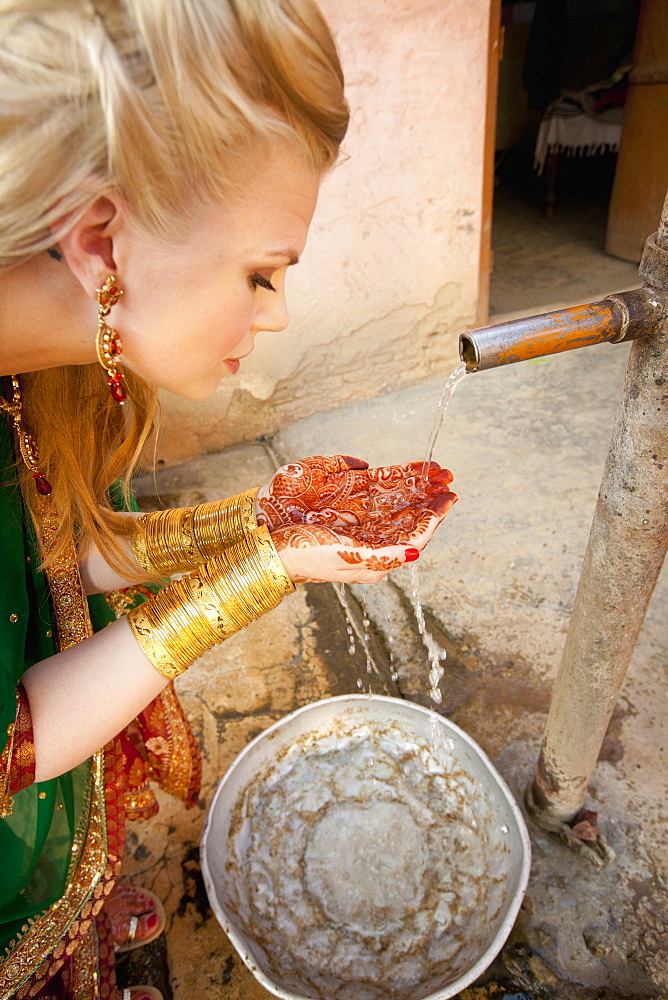 A Woman With Mehndi On Her Palms Cups Her Hands To Collect Water From A Tap, Ludhiana, Punjab, India