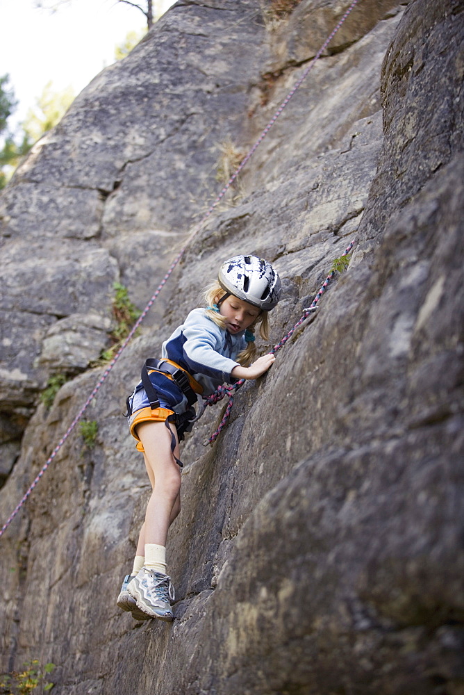 Young Girl (Age 7) Climbing On Granite Cliff At Stone Hills Near Rexford, Montana, Usa