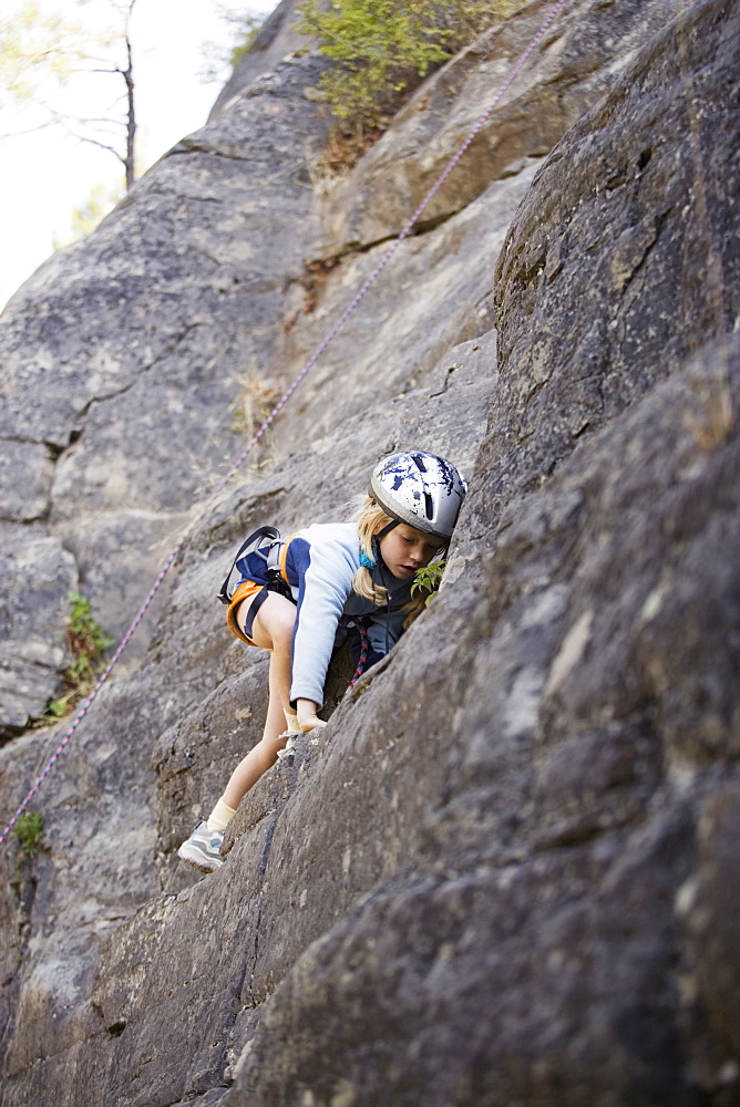 Young Girl (Age 7) Climbing On Granite Cliff At Stone Hills Near Rexford, Montana, Usa