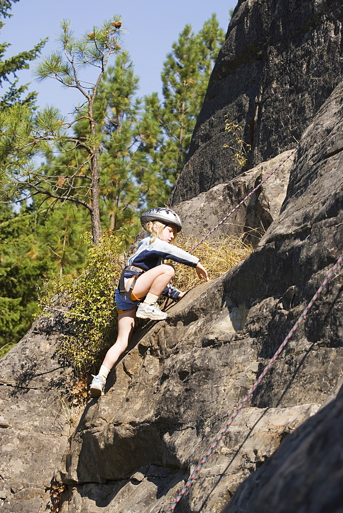 Young Girl (Age 7) Climbing On Granite Cliff At Stone Hills Near Rexford, Montana, Usa