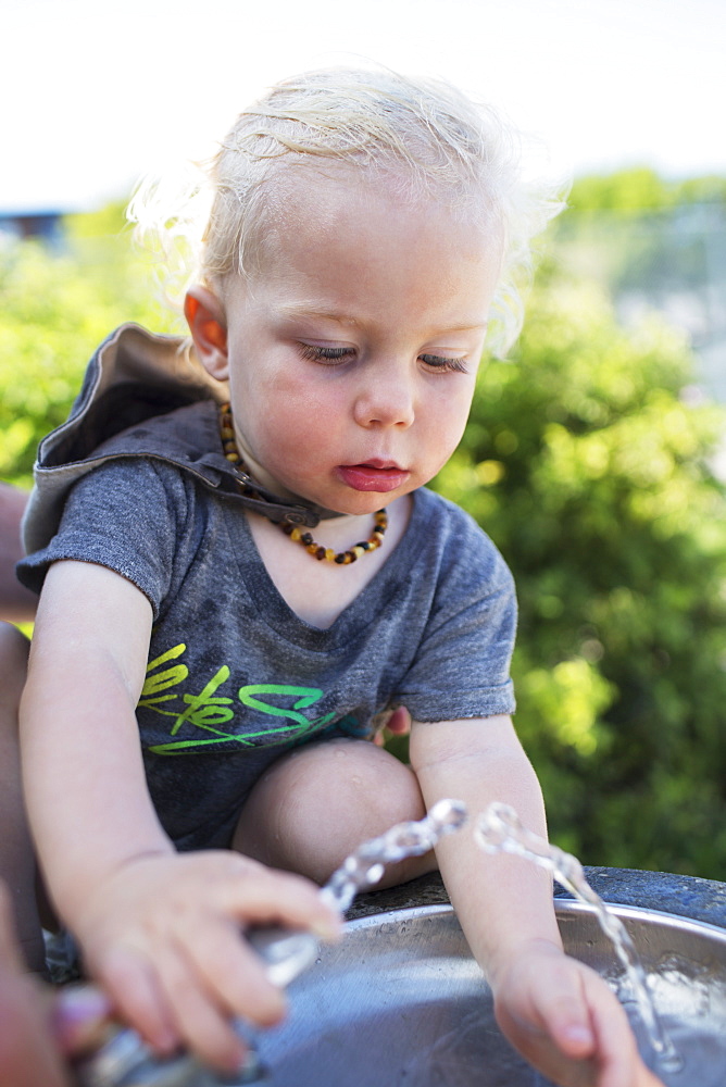 Young Boy At The Drinking Fountain On A Hot Summer Day, Toronto, Ontario, Canada