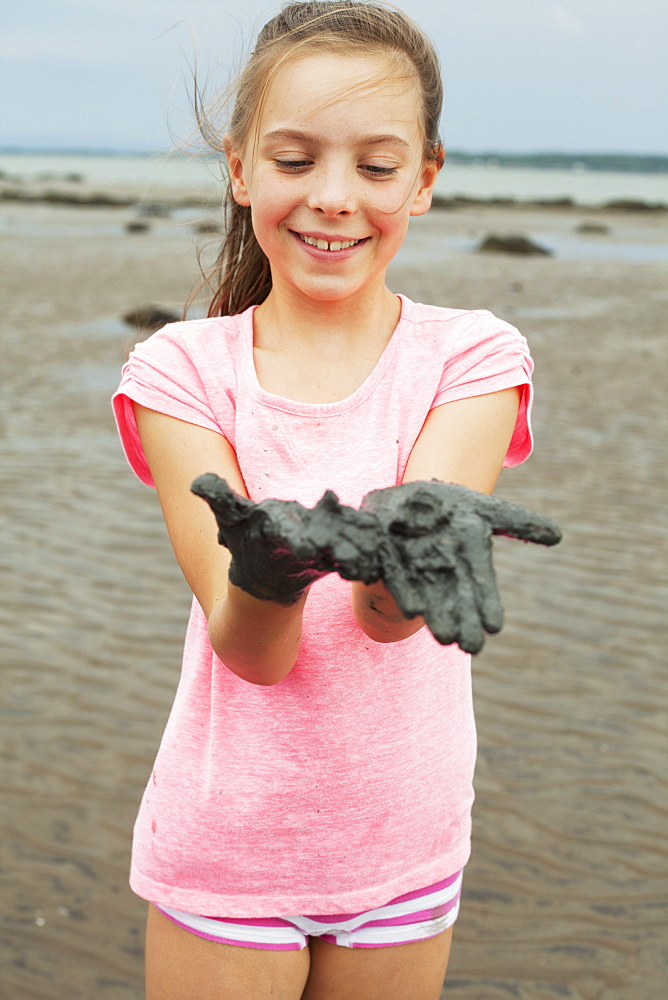 Young Girl Wearing Pink On A Shore Showing Her Muddy Hands, Charlevoix, Quebec, Canada