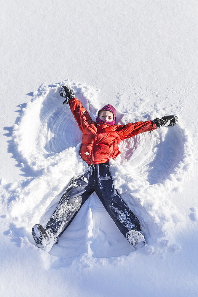 Young Girl Making A Snow Angel In Wintertime, Talkeetna, Alaska, United States Of America