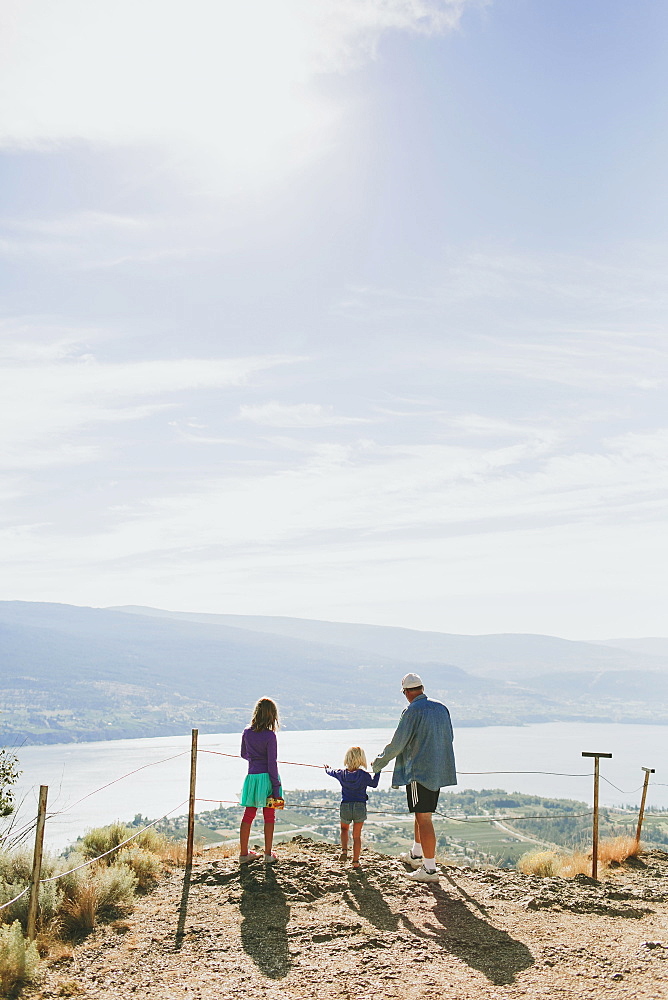 A Family Stands Together Overlooking A View Of Lake Okanagan, Peachland, British Columbia, Canada