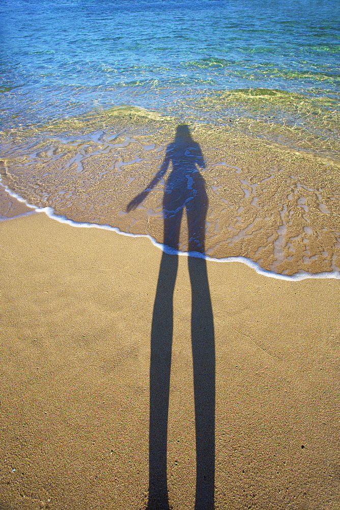 Shadow Of A Woman Standing On The Beach At The Water's Edge, Kauai, Hawaii, United States Of America