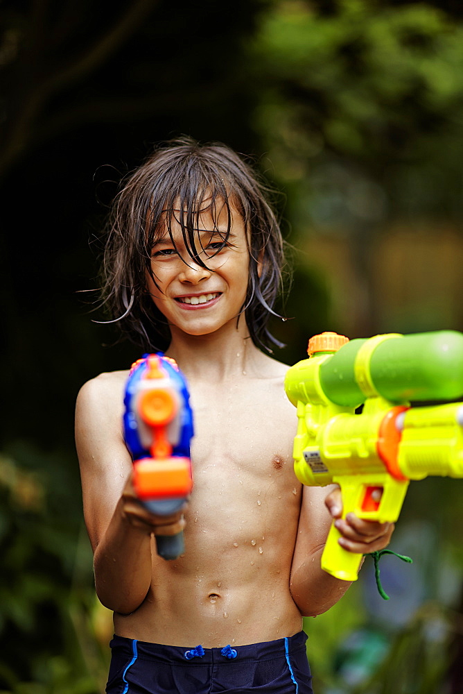 Young Boy Playing With Water Guns, Markham, Ontario, Canada