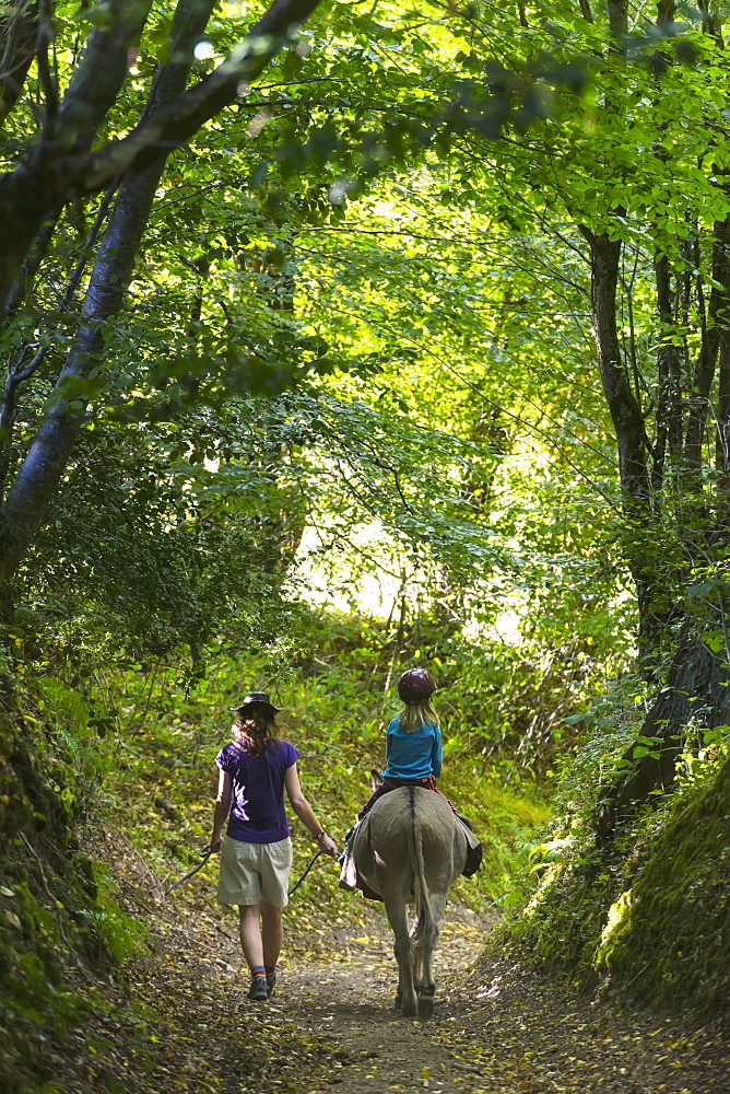 Mother With Girl On Donkey Walking Along A Trail, Normandy, France