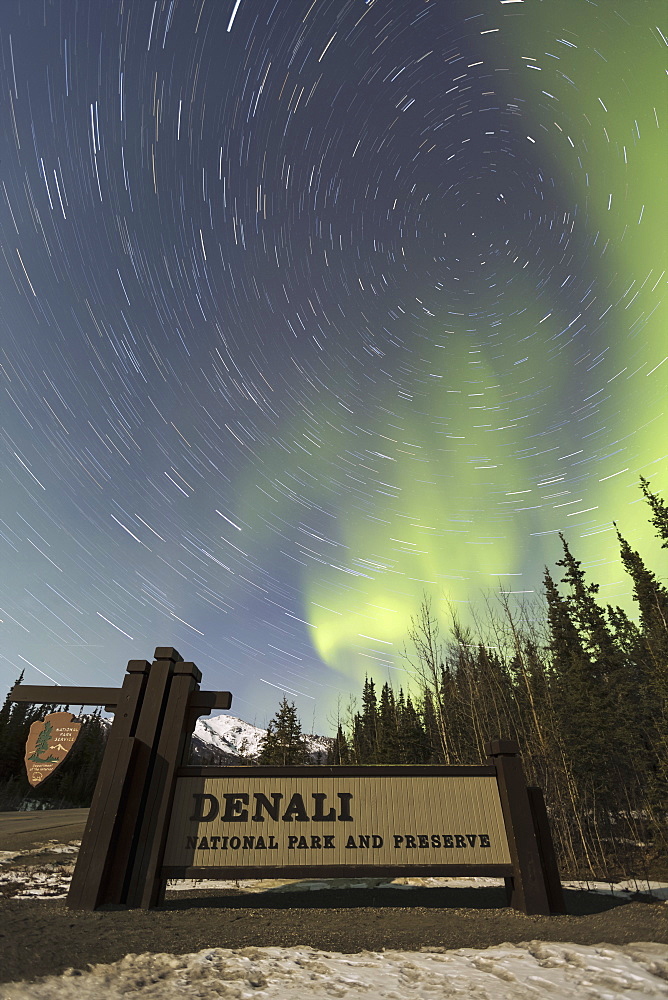 The Aurora Borealis (Northern Lights) And Stars Circling Above The Sign Marking The Entrance To Denali National Park And Preserve, Alaska, United States Of America