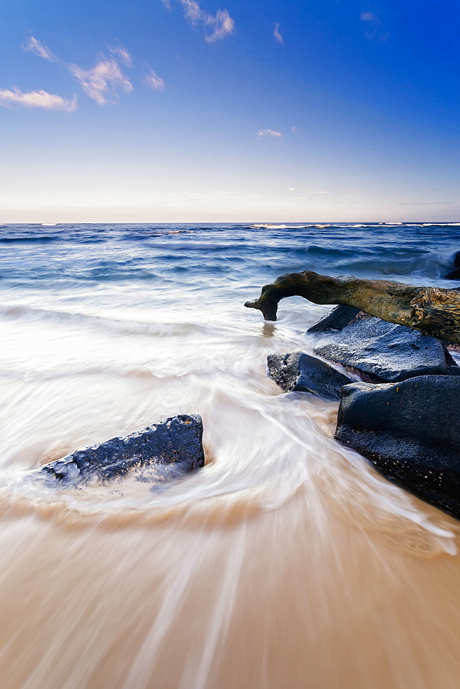 Surf Washing Up Around Driftwood And Rocks, Wailua, Kauai, Hawaii, United States Of America