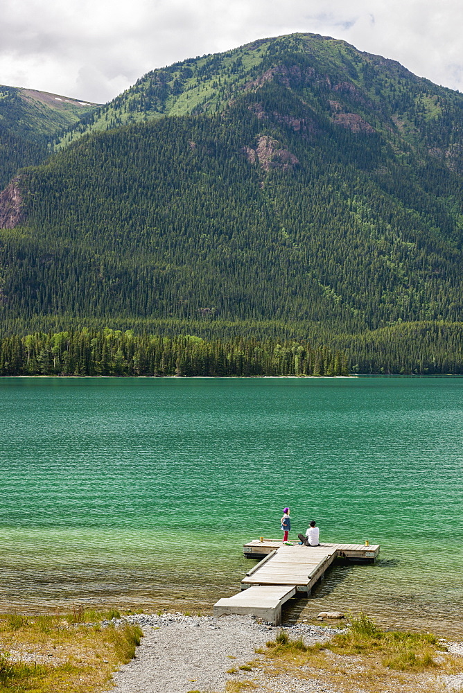 Mother And Daughter On A Dock At Muncho Lake Provincial Park, British Columbia, Canada, Summer