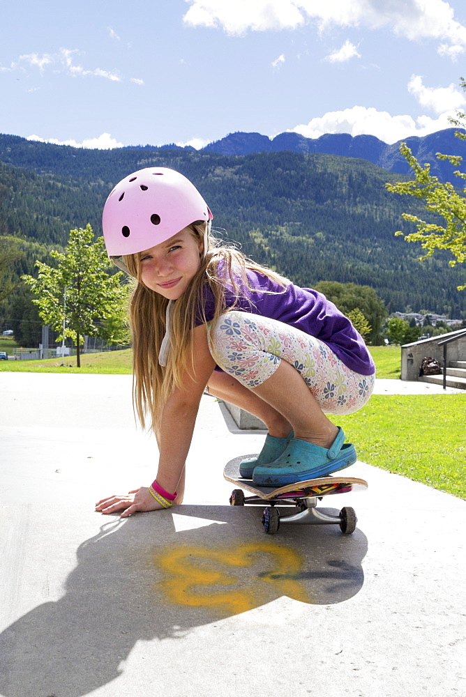 Young Girl On A Skateboard Wearing A Pink Helmet, Salmon Arm, British Columbia, Canada