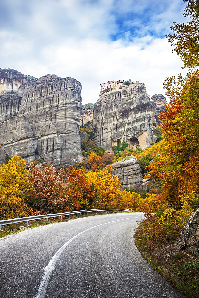 Monastery Perched On A Cliff, A Road And Autumn Foliage, Meteora, Greece