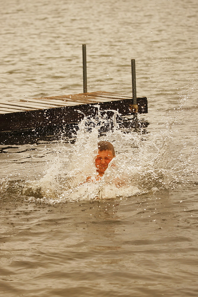 Boy In Water After Jumping Off Dock In A Lake