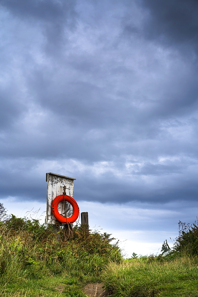 Red Ring Life Preserver Hanging On A Wooden Post, Northumberland, England