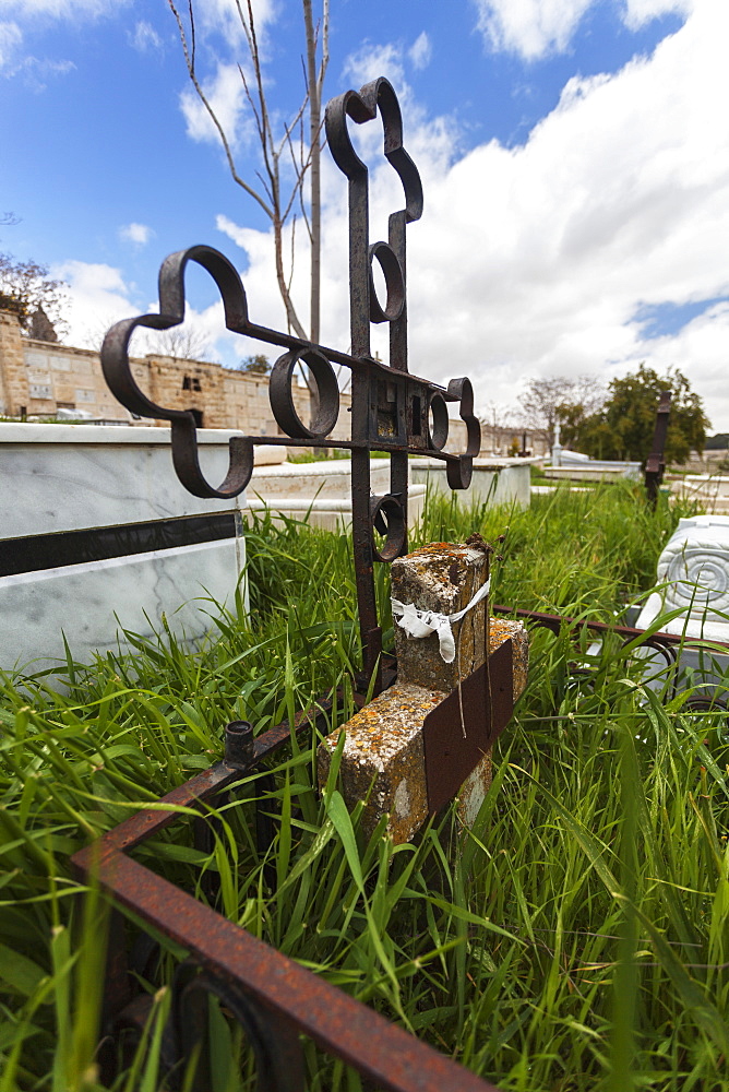 Metal Cross Headstone With Overgrown Grass In A Cemetery, Israel