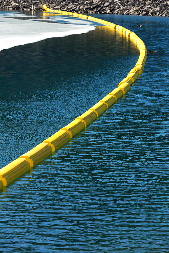 Yellow Buoy Across The Water With Rocky Shoreline And Ice On Lake, Kananaskis Country, Alberta, Canada