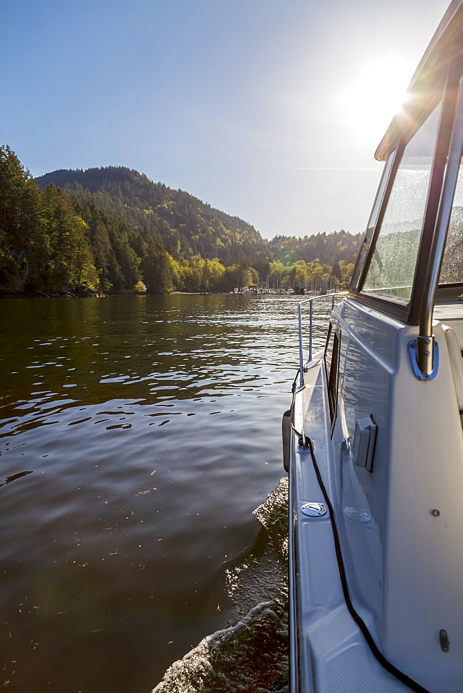 The view of the entrance to Snug Cove on Bowen Island as this boat approaches the marina late in the day when the sun is setting, Bowen Island, British Columbia, Canada