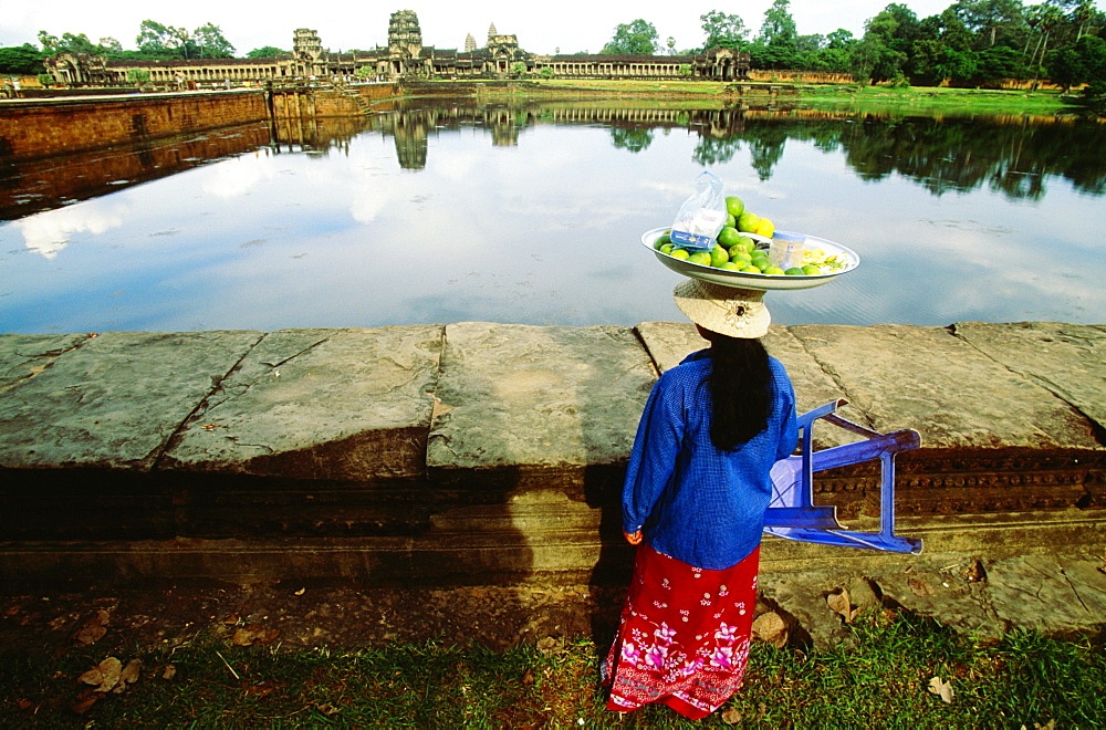 Rear view of a female vendor carrying lime fruit on her head, Angkor Wat, Angkor, Siem Reap, Cambodia