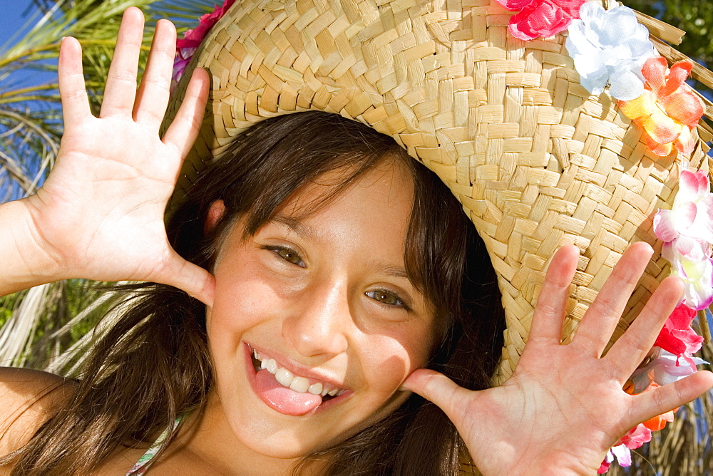 Portrait of a girl wearing a straw hat and sticking her tongue out