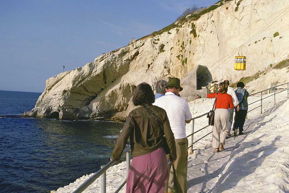 Rear view of a group of tourists walking towards an overhead cable car station, Israel