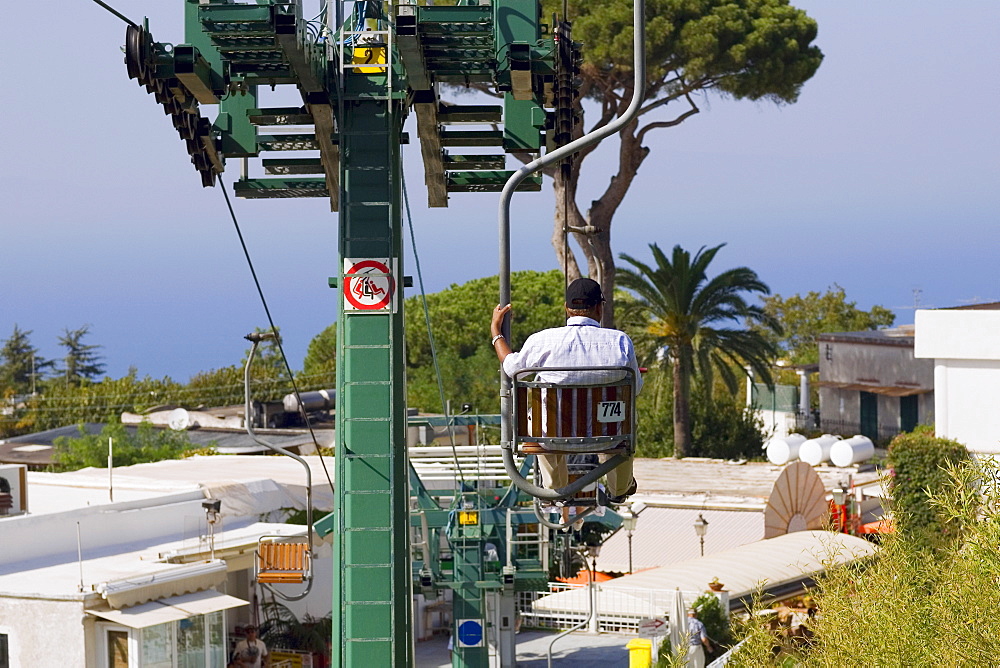 Rear view of a man sitting in an overhead cable car, Capri, Campania, Italy