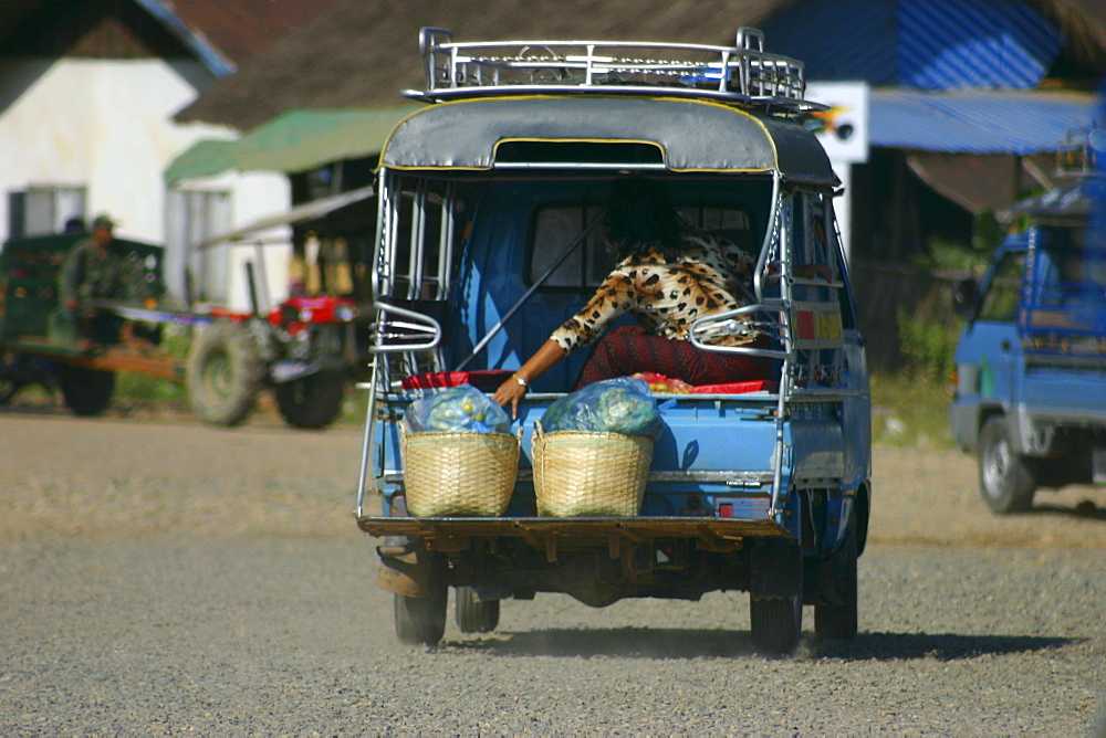 Passenger traveling in a jinrikisha, Vang Vieng, Laos