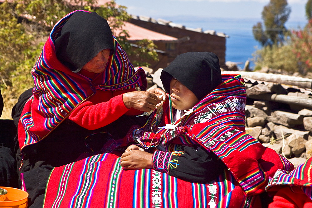 Mid adult woman grooming a bride for wedding, Taquile Island, Lake Titicaca, Puno, Peru