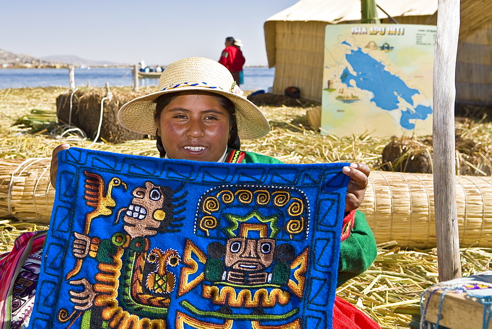 Portrait of a young woman showing a decorated blanket, Peru