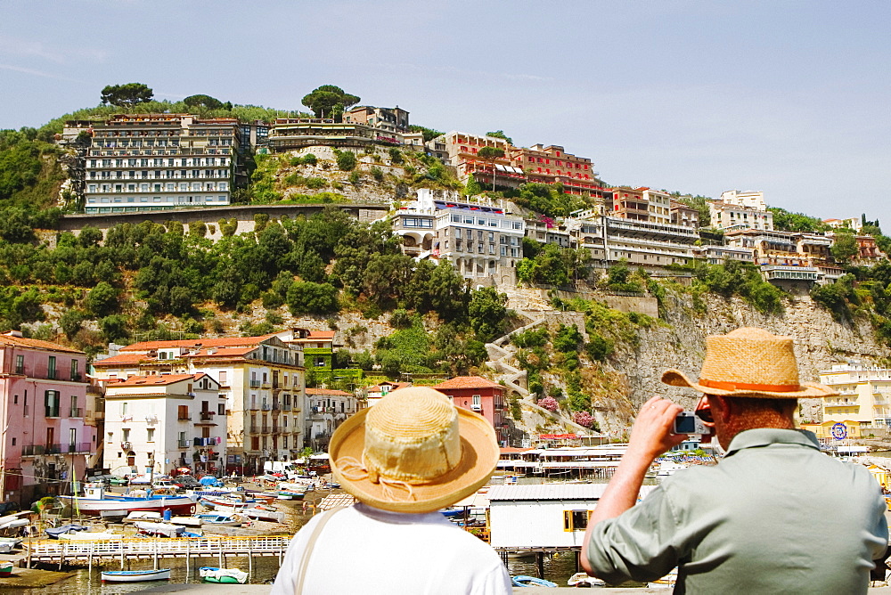 Rear view of tourists photographing a harbor, Marina Grande, Capri, Sorrento, Sorrentine Peninsula, Naples Province, Campania, Italy