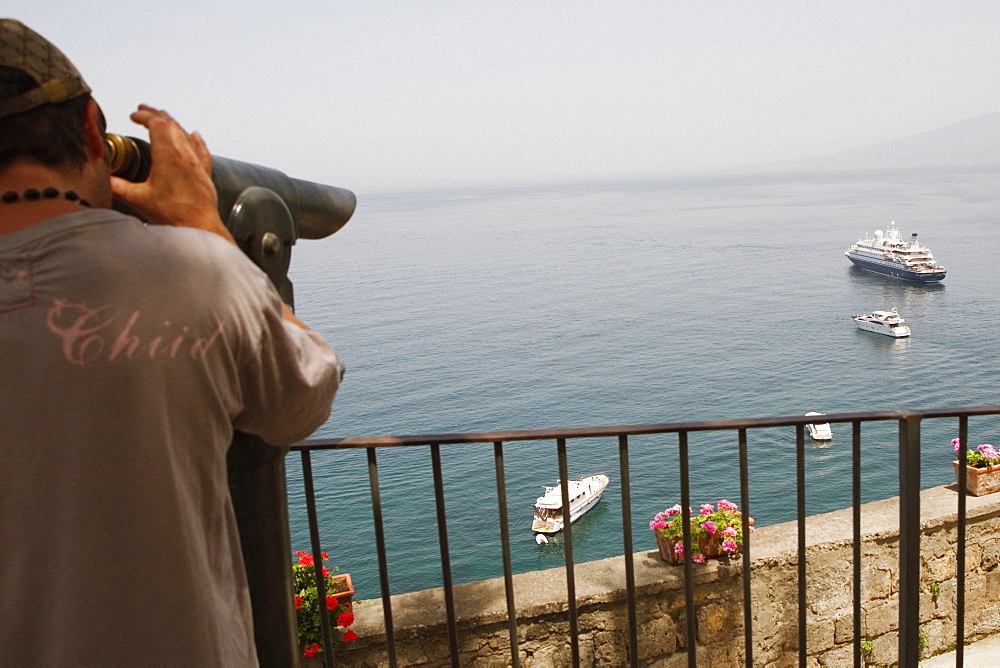 Rear view of a man looking through a coin-operated binocular, Bay of Naples, Via Aniello Califano, Sorrento, Sorrentine Peninsula, Naples Province, Campania, Italy