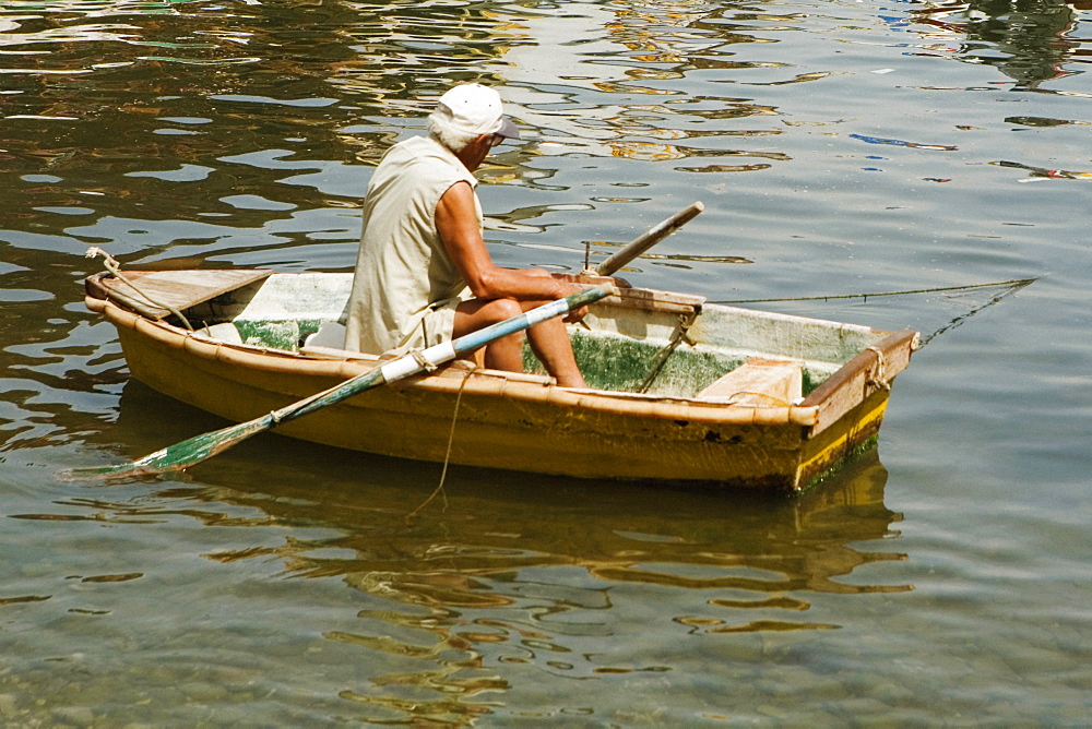 Rear view of a man sitting in a boat, Marina Grande, Capri, Sorrento, Sorrentine Peninsula, Naples Province, Campania, Italy