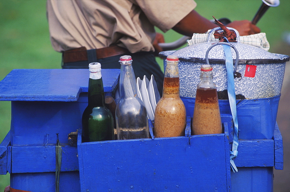 Mid section view of a man carrying a wooden box with bottles and a container on a bicycle