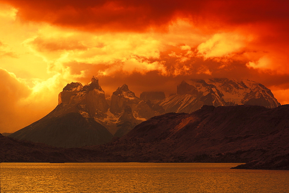 Rainy clouds over mountains by the sea at dusk