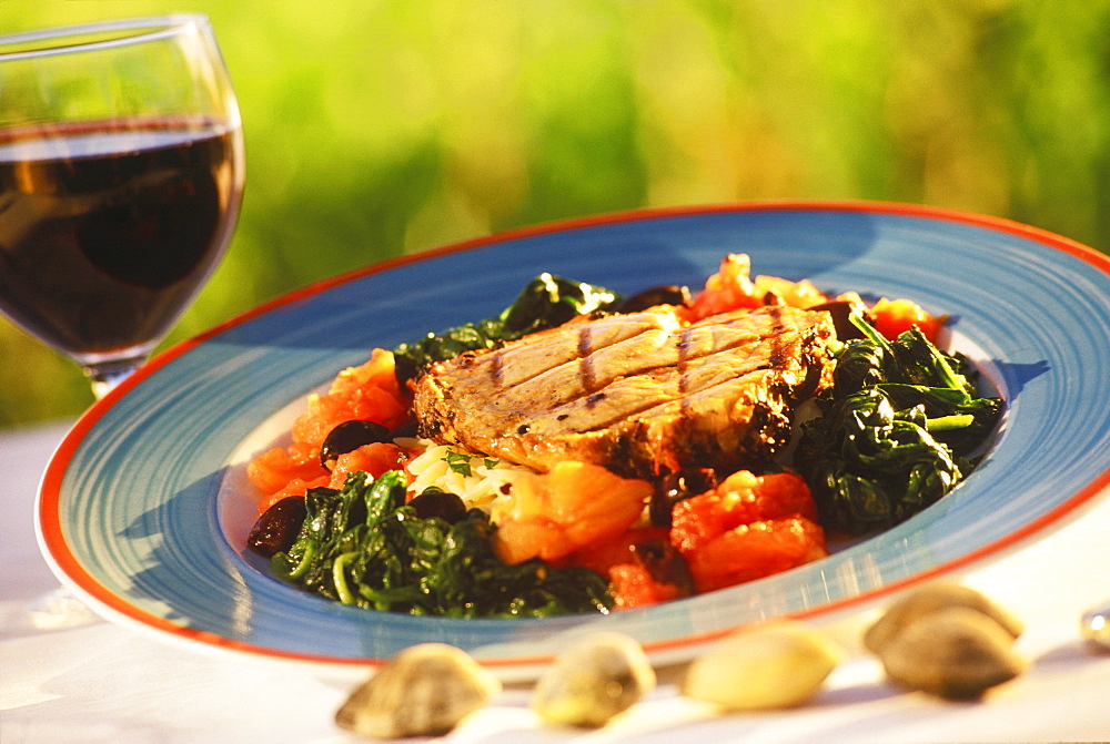 Close-up of grilled vegetables with nuts and a glass of red wine