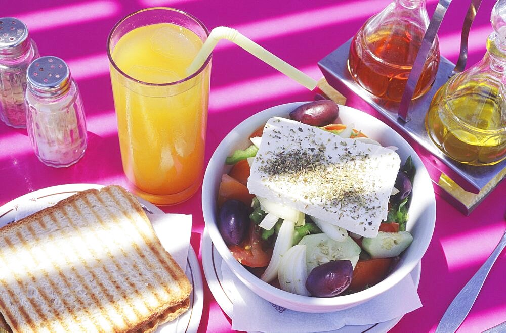 Close-up of a salad bowl with a glass of juice on the table