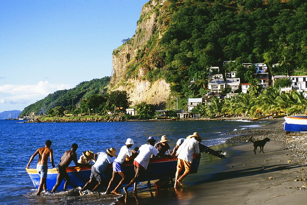 Natives pushing a boat onto a shore near the town of Castries, St. Lucia