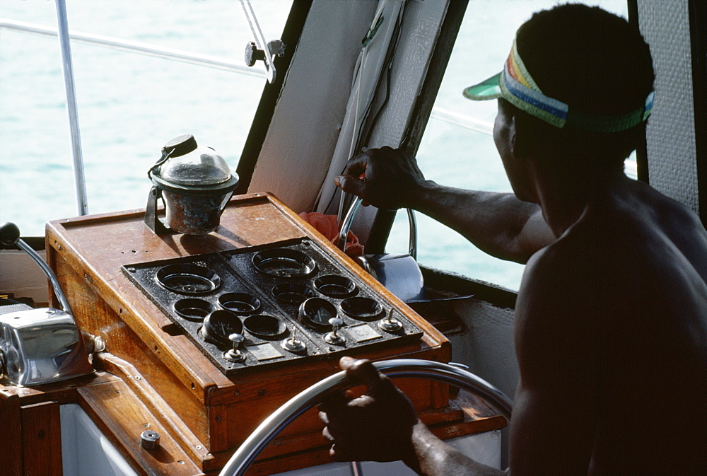 A boat captain navigates a powerboat off the shore of Jamaica