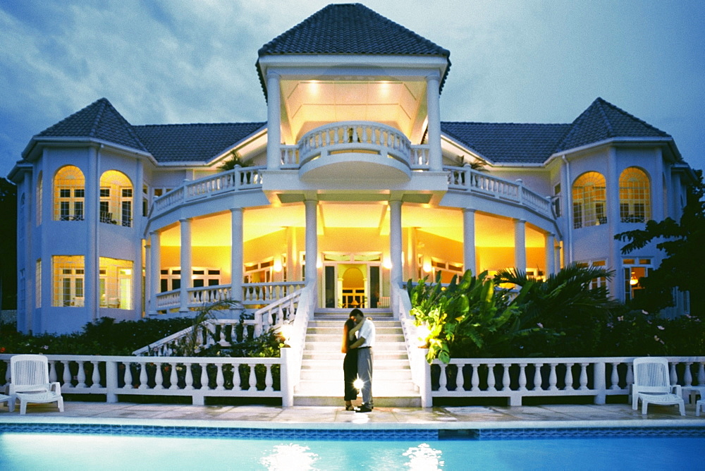 A couple kiss in front of the illuminated Endless Summer Villa, Jamaica