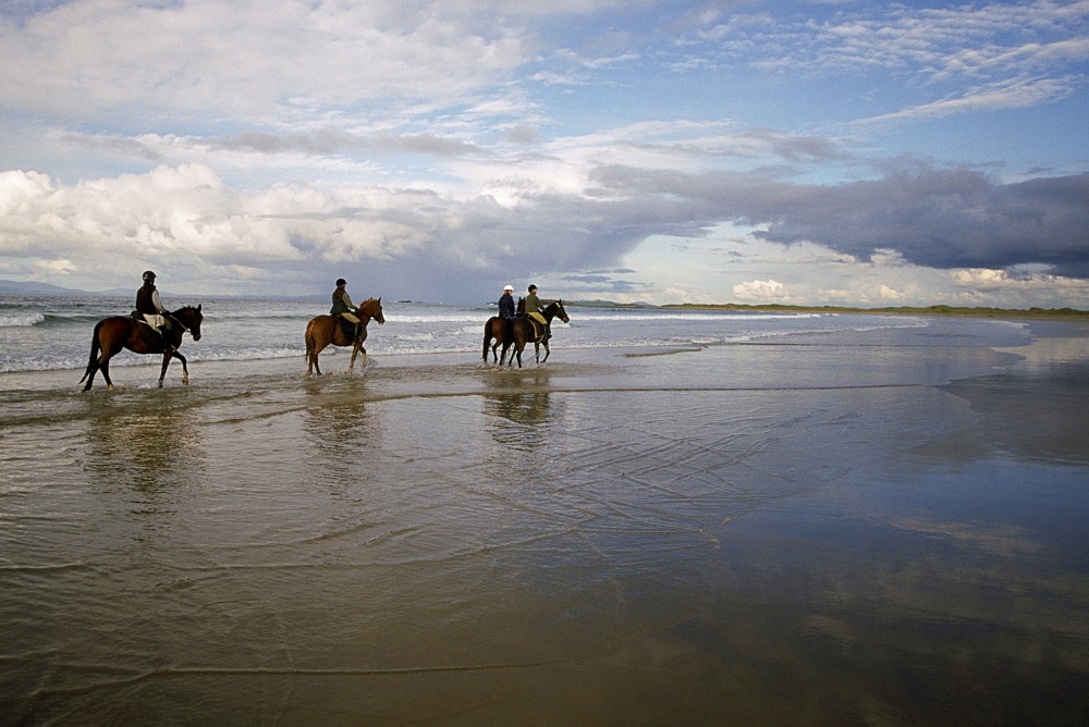 Four people horseback riding on the beach, Sligo, Republic of Ireland