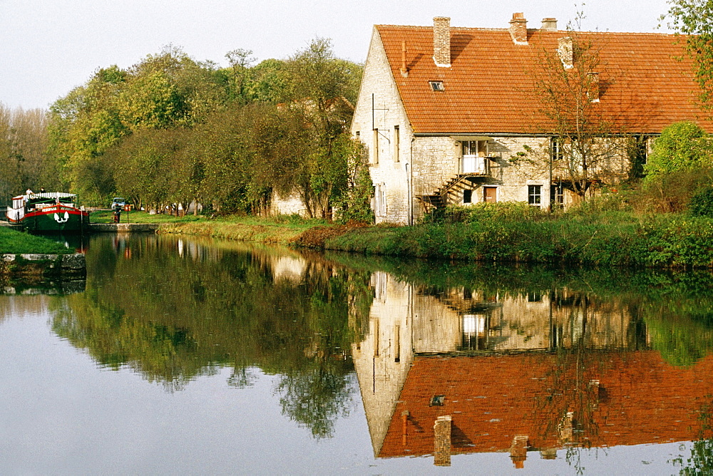 View of a barge moving upstream and passing by a farmhouse, Burgundy River, France