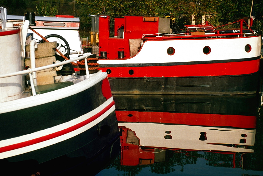 Two river barges dry-docked on a calm river, France