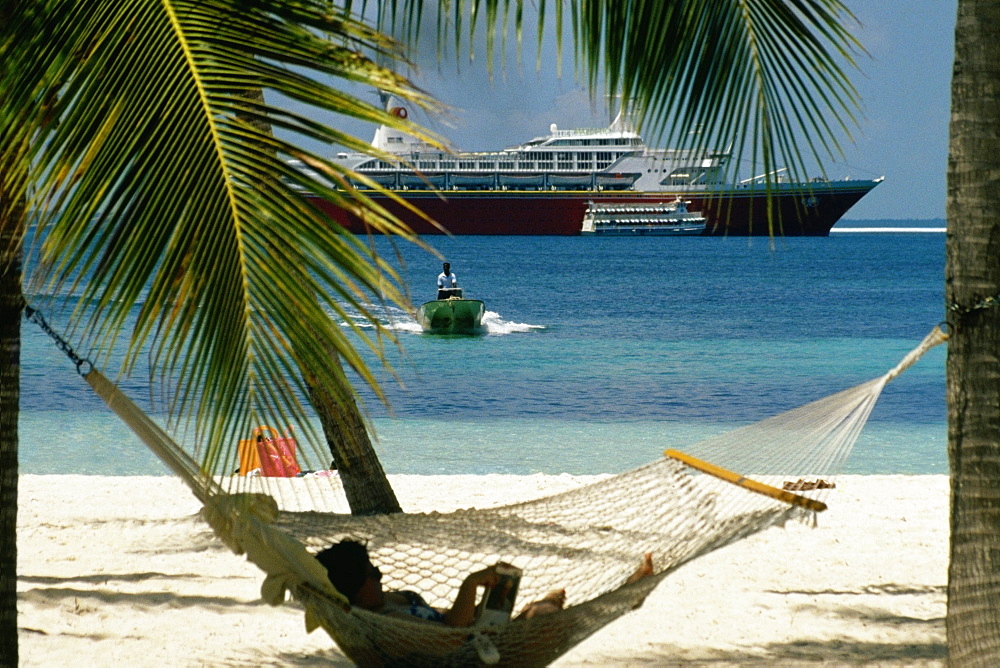 A woman relaxing on a hammock on a beach, Treasure Island, Abaco, Bahamas