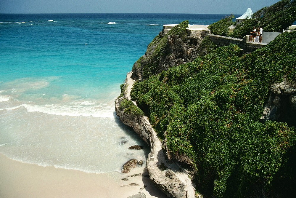 A rugged rock formation is seen next to a beach at Barbados coast, Caribbean