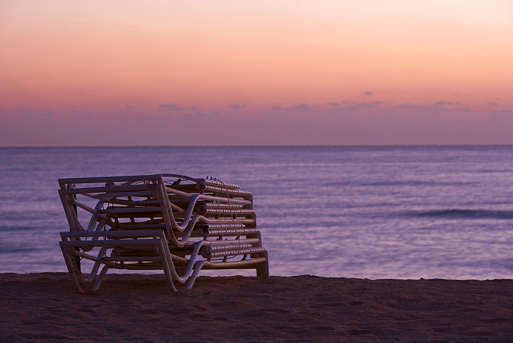 Stack of folded lounge chairs on the beach