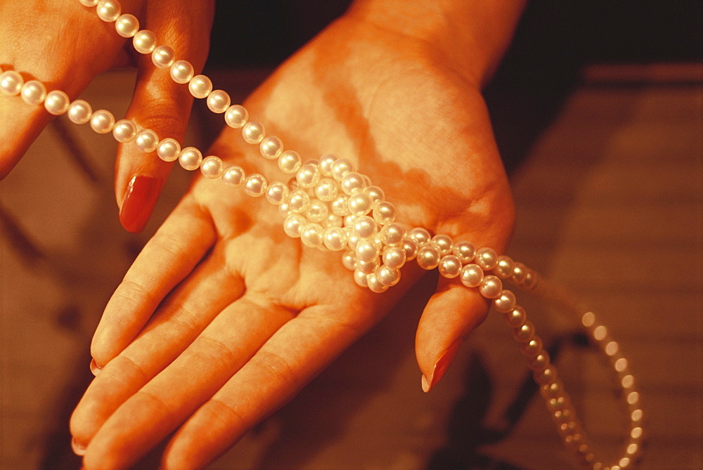 Close-up of a necklace of Mikimoto pearls in a woman's hand