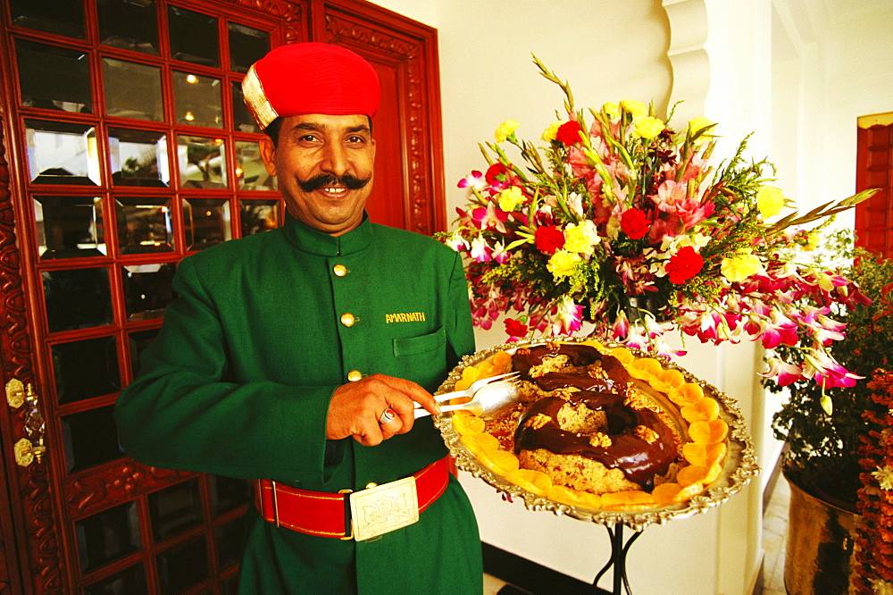 Portrait of a waiter holding a dish plate and smiling, Lake Palace, Udaipur, Rajasthan, India